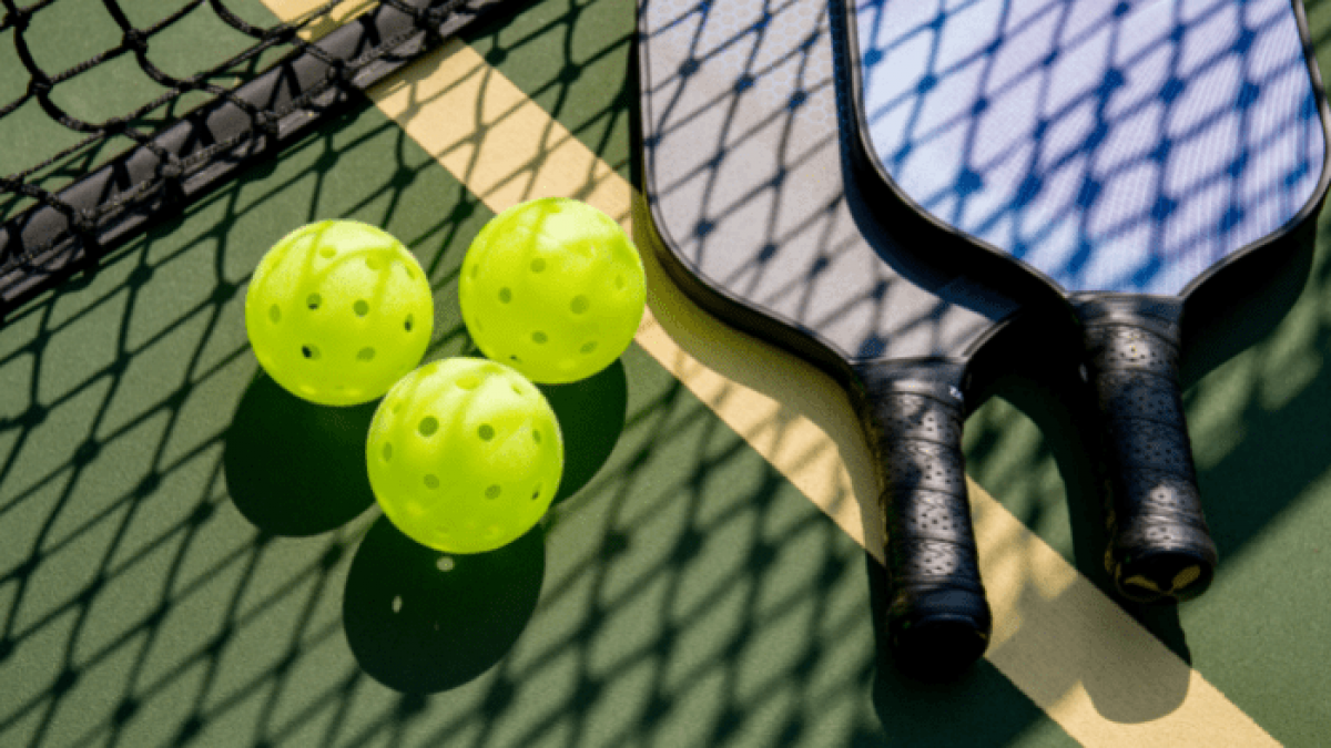 Quadra de pickleball com raquetes e bolas